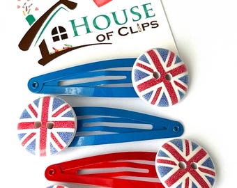 May include: Four hair clips with a Union Jack design. The clips are red, blue, and white. The clips are decorated with a button in the center.
