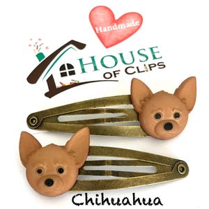 May include: Two bronze-toned hair clips, each adorned with a brown Chihuahua dog head. The clips are set against a white background, with the word "Chihuahua" written in black script below. The House of Clips logo is visible.