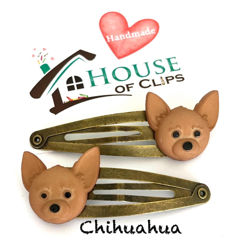 May include: Two bronze-toned hair clips, each adorned with a brown Chihuahua dog head. The clips are set against a white background, with the word "Chihuahua" written in black script below. The House of Clips logo is visible.