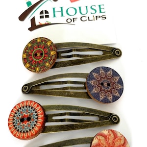 Puede incluir: Cuatro horquillas para el pelo de color bronce antiguo con botones decorativos de madera. Los botones presentan intrincados diseños en rojo, azul y naranja. La imagen incluye el texto "Handmade" y "HOUSE OF CLIPS".