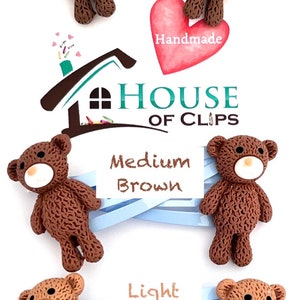 May include: Three teddy bear hair clips in different shades of brown: dark brown, medium brown, and light brown. The clips are handmade and feature a house logo with the text "House of Clips".