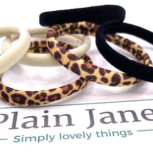May include: A set of four hair ties, two are black, one is beige, and one is brown with a leopard print.