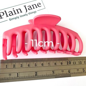 Puede incluir: Una pinza para el pelo de pl&aacute;stico rosa brillante que mide 11 cm de largo. La pinza tiene varios dientes para sujetar el pelo en su lugar.