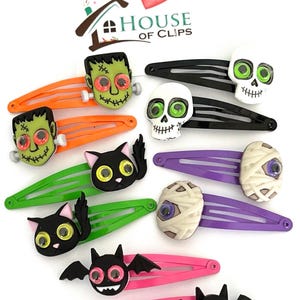 Pode incluir: Conjunto de 10 presilhas de cabelo com tema de Halloween que representam v&aacute;rios personagens como uma caveira, um gato, um morcego, uma m&uacute;mia e Frankenstein. Cada presilha tem olhos saltitantes e &eacute; feita de pl&aacute;stico. As presilhas s&atilde;o de v&aacute;rias cores, incluindo preto, laranja, verde, roxo, rosa e branco.