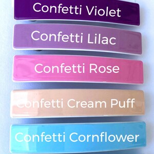 May include: Six colorful hair clips with the words "Confetti Violet", "Confetti Lilac", "Confetti Rose", "Confetti Cream Puff", "Confetti Cornflower", and "Confetti Limelight" printed on them.