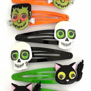 Pode incluir: Conjunto de 8 prendedores de cabelo de Halloween com v&aacute;rios personagens com olhos saltitantes. Os personagens incluem um morcego, uma m&uacute;mia, uma caveira, um Frankenstein e um gato preto. Os prendedores s&atilde;o feitos de pl&aacute;stico e t&ecirc;m um design colorido. Feito &agrave; m&atilde;o pela House of Clips.