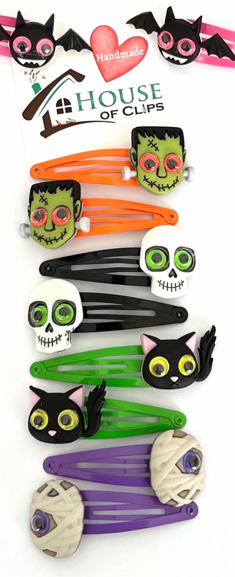 Pode incluir: Conjunto de 8 prendedores de cabelo de Halloween com v&aacute;rios personagens com olhos saltitantes. Os personagens incluem um morcego, uma m&uacute;mia, uma caveira, um Frankenstein e um gato preto. Os prendedores s&atilde;o feitos de pl&aacute;stico e t&ecirc;m um design colorido. Feito &agrave; m&atilde;o pela House of Clips.