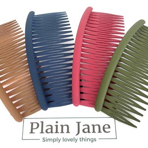 Op de afbeelding: Vier kleurrijke haar kammen in bruin, blauw, roze en groen zijn gerangschikt op een witte achtergrond. De kammen hebben een gebogen ontwerp met dicht bij elkaar geplaatste tanden. De merknaam "Plain Jane" is zichtbaar onderaan.