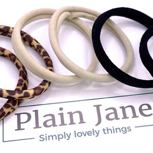 May include: A set of six hair ties in three different patterns: leopard print, beige, and black. The hair ties are made of soft, stretchy fabric and are perfect for holding up hair.