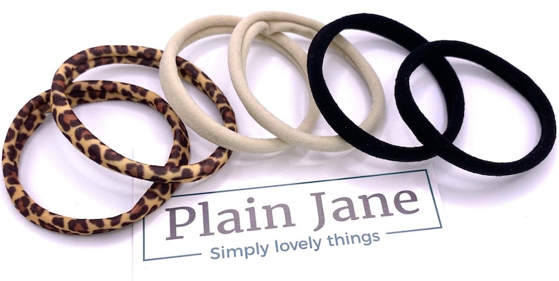 May include: A set of six hair ties in three different patterns: leopard print, beige, and black. The hair ties are made of soft, stretchy fabric and are perfect for holding up hair.