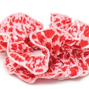 May include: A pink and red patterned hair scrunchie with a ruffled design.