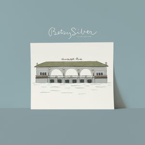 Könnte beinhalten: Illustration des Humboldt Parks, mit einem grauen Gebäude mit gewölbten Öffnungen und einem grünen Dach. Das Kunstwerk ist mit "Betsy Silver Illustration" in Kursivschrift signiert. Der Text "Humboldt Park" steht unter dem Gebäude.