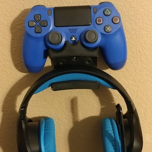 May include: A blue PlayStation 4 controller and a pair of blue and black headphones are mounted on a wall.