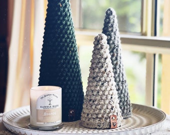 May include: Three crocheted Christmas trees on a white tray with a candle that says "The German Village Candle Haus Handmade in Lancaster, PA" and "Eggnog".