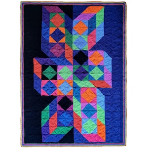 May include: A large, colorful crochet blanket with a geometric design. The blanket features a black background with a central pattern of squares and diamonds in shades of blue, orange, green, purple, and pink. The border is a mix of colors.