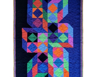 May include: A large, colourful crochet blanket with a geometric design. The blanket features a black background with a central pattern of squares and diamonds in shades of blue, orange, green, purple, and pink. The border is a mix of colours.