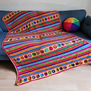 May include: A colorful crocheted throw blanket with a striped pattern and circular designs. The blanket is made with a variety of bright colors, including red, orange, yellow, green, blue, and purple.