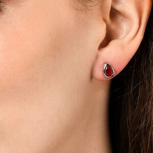 Peut inclure: Une paire de boucles d'oreilles en argent avec une pierre rouge en forme de larme.