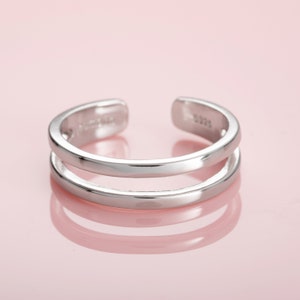 May include: A silver double band ring with a smooth, polished finish.