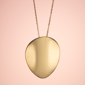 Puede incluir: Un collar de oro con un colgante liso en forma de lágrima.