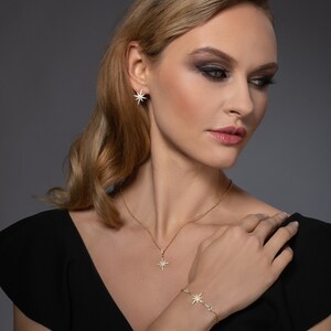 May include: A gold necklace and bracelet set with a starburst pendant and matching earrings. The jewelry features a delicate chain and sparkling stones.