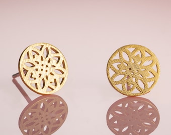 May include: A pair of gold-toned earrings with a delicate, intricate floral design. The earrings are round and have a cutout pattern.