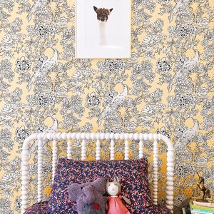 Pu&ograve; includere: Un letto bianco con una testata e un piede a baldacchino bianchi. La testata ha un design decorativo di piccole perline bianche. Il letto &egrave; fatto con biancheria da letto a motivi floreali blu scuro e rosa. Due animali di peluche, un elefante grigio e un gatto rosa, sono seduti sul letto. La parete dietro il letto &egrave; rivestita di carta da parati gialla con un motivo floreale bianco e nero.