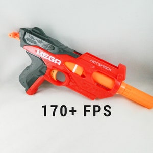 Op de afbeelding: Een rode en grijze speelgoedblaster met de tekst "MEGA" en "HOTSHOCK". De blaster heeft een oranje loop en de tekst "170+ FPS" wordt eronder weergegeven.
