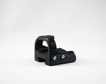 May include: A black plastic red dot sight with a flip-up rear sight. The sight has two small screws on the top.