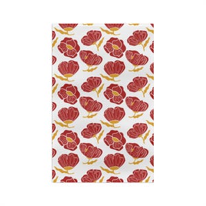May include: White rectangular kitchen towel with a repeating pattern of red flowers with yellow accents. The flowers have a detailed, hand-drawn appearance, creating a charming and artistic design. The towel is likely made of absorbent fabric.