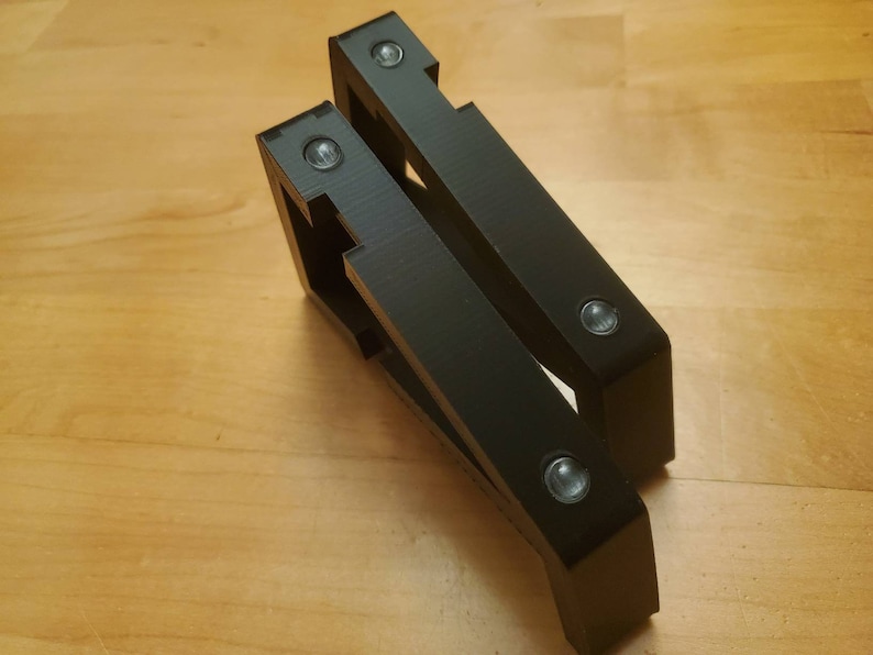 Puede incluir: Dos soportes de estante de pl&aacute;stico negro con cuatro agujeros de tornillo visibles.