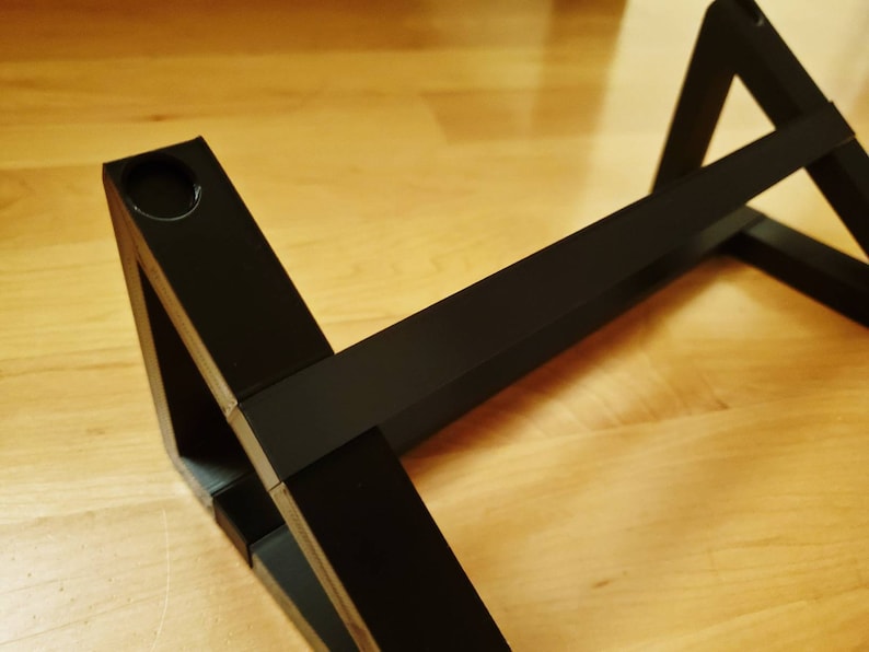 Puede incluir: Estante triangular negro con un agujero en una de las esquinas. El estante est&aacute; hecho de madera y tiene un acabado negro.