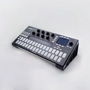 May include: A black and gray MIDI controller with white keys and knobs. The device has a small screen and is labeled "ATOM SQ". The controller is designed for music production and performance.
