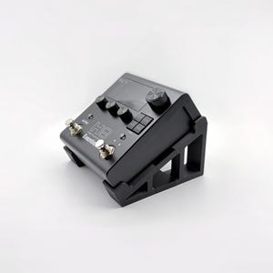 Könnte beinhalten: Ein schwarzes Eventide H9 Gitarreneffektpedal auf einem schwarzen, abgewinkelten Ständer. Das Pedal verfügt über ein digitales Display, drei Drehregler, einen großen Drehgeber und zwei metallische Fußschalter. Die Schriftzüge H9 und Eventide sind aufgedruckt.