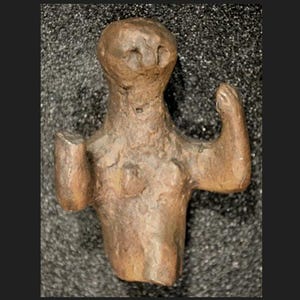 May include: A small, bronze-colored figurine of a human form. The figure has a rounded head, a torso with breasts, and arms raised in different positions. The surface has a rough, textured appearance, suggesting an aged or antique quality.