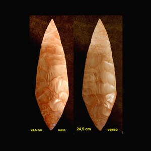 Könnte beinhalten: Ein hellbrauner, spitzer Steinpfeilspitz mit einer strukturierten Oberfläche. Der Pfeilspitz ist 24,5 cm lang. Das Bild zeigt beide Seiten des Pfeilspitzes, beschriftet mit "recto" und "verso".