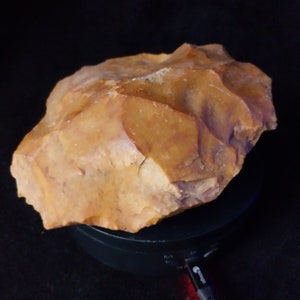 May include: A large, irregularly shaped, orange and purple stone with a rough, textured surface. The stone is likely a hand-crafted tool or artifact.