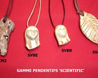 May include: Four pendants on leather cords, each with a different design. The pendants are made of a light brown material and are carved with intricate details. The pendants are labeled "SCMZ", "SVBE", "SVBR", and "SSLE". The image also includes the text "GAMME PENDANTIFS 'SCIENTIFIC'".