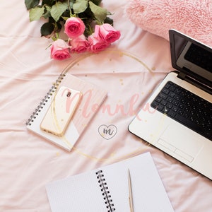 Styled Stock Photo.  Roses, laptop, notebooks and smartphone in bed on pink sheets. Freelance fashion home femininity workspace in flat lay