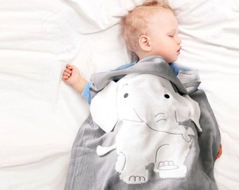 May include: A gray knitted baby blanket with a white elephant design and the name "Alex" embroidered on it. The blanket is soft and cuddly, perfect for a baby.