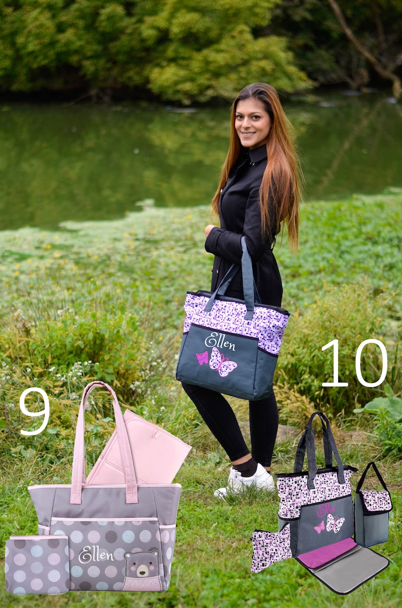 May include: Two gray and purple tote bags with the name "Ellen" embroidered on them. The bags have different patterns, one with butterflies and the other with polka dots and a bear. Both bags have a zippered pocket and a changing pad.