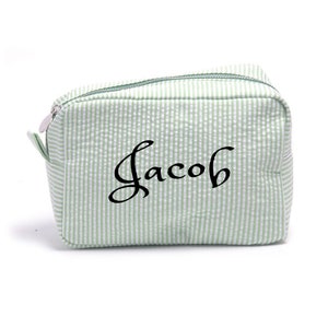May include: A green and white striped toiletry bag with the name "Jacob" embroidered in black.