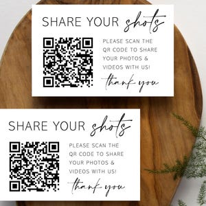 May include: Two white cards with black text and a black and white QR code. The text on the cards reads "SHARE YOUR shots" and "PLEASE SCAN THE QR CODE TO SHARE YOUR PHOTOS & VIDEOS WITH US! thank you".