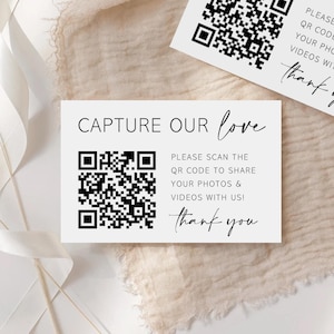 May include: A white rectangular card featuring the black text CAPTURE OUR love and PLEASE SCAN THE QR CODE TO SHARE YOUR PHOTOS & VIDEOS WITH US! thank you, alongside a black and white QR code. A second identical card is partially visible above.