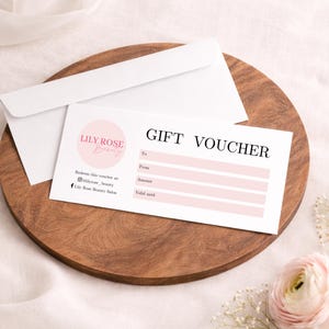 May include: A white gift voucher with a pink circular logo reading Lily Rose Beauty, featuring fields for To, From, Amount, and Valid until. The voucher includes social media handles for Instagram and Facebook, accompanied by a matching white envelope.