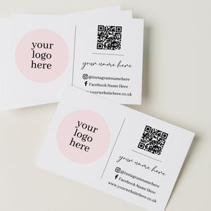 Peut inclure: Une pile de cartes de visite rectangulaires blanches avec un cercle rose clair sur la gauche portant le texte your logo here. La partie droite présente un QR code noir, le texte your name here, des icônes de réseaux sociaux et un site web.