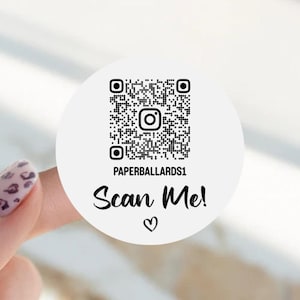 May include: A circular white sticker featuring a black QR code with a central Instagram icon. Below the code, the text reads PAPERBALLARDS1, followed by the phrase Scan Me! in a script font and a small hand-drawn heart symbol at the bottom.