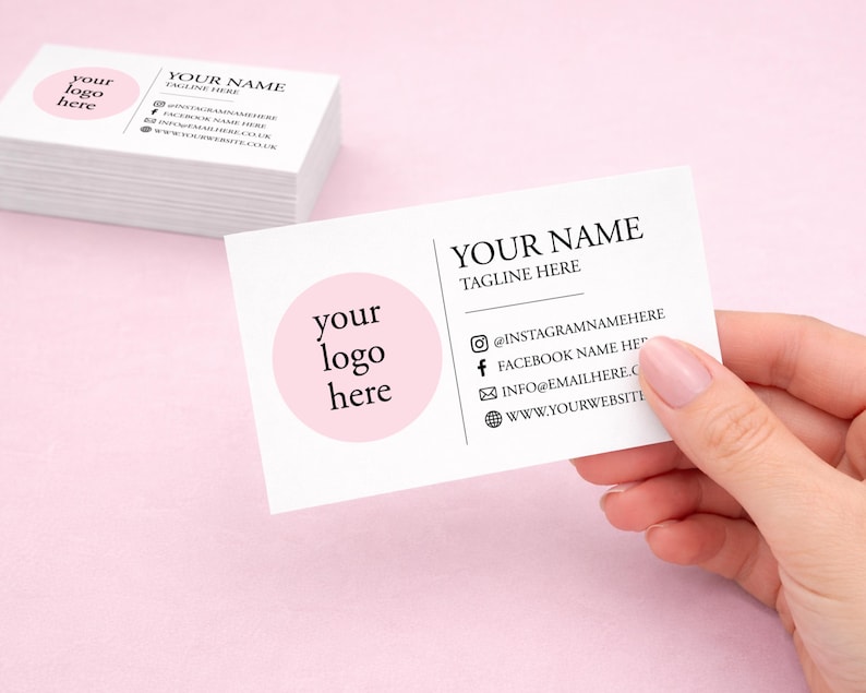 K&ouml;nnte beinhalten: Ein Stapel wei&szlig;er Visitenkarten und eine einzelne Karte mit einem rosa Kreis und dem Text 'your logo here' auf der linken Seite. Rechts stehen 'YOUR NAME', 'TAGLINE HERE' sowie Symbole f&uuml;r Instagram, Facebook, E-Mail und Website.