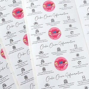 Peut inclure: Une feuille d'autocollants rectangulaires blancs avec le texte Cake Care Information et le logo LK Bakes dans un cercle rose. Chaque autocollant pr&eacute;sente des ic&ocirc;nes noires et des instructions pour transporter, conserver et servir les g&acirc;teaux.