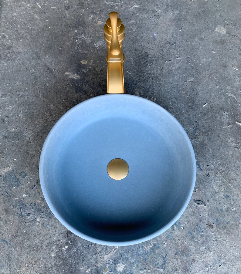 May include: A round, light blue ceramic sink with a gold faucet and drain.